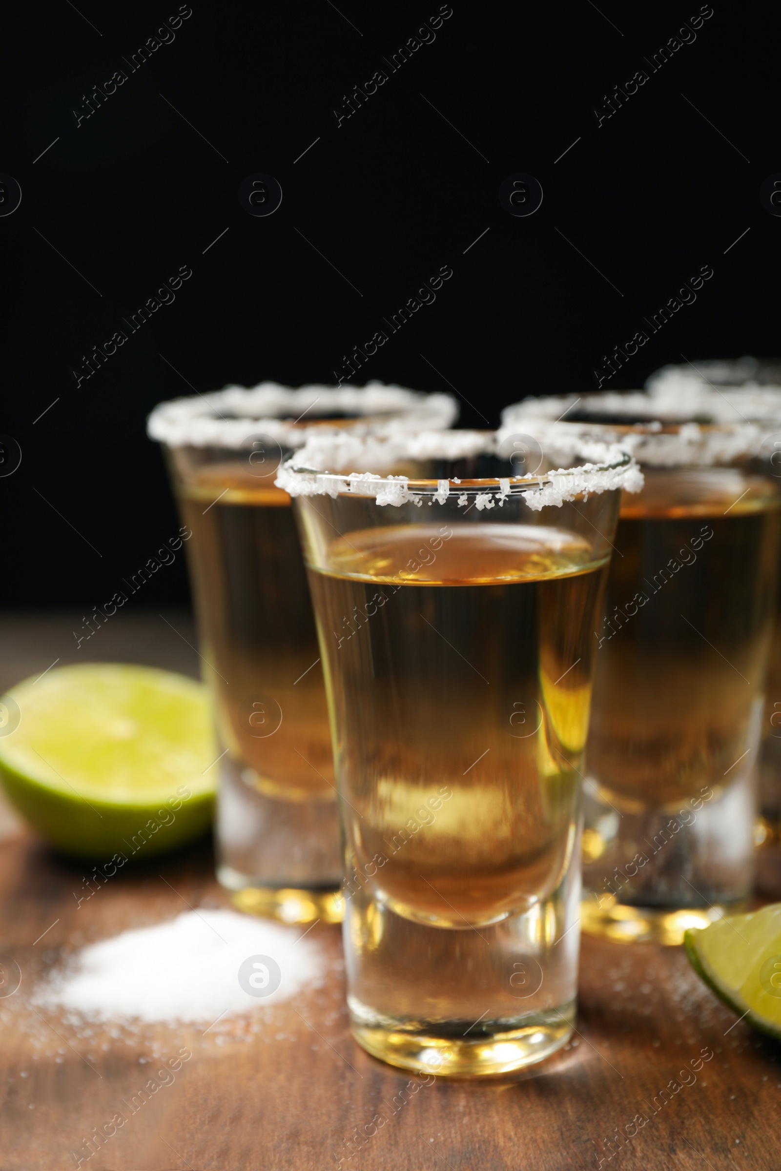 Photo of Mexican Tequila shots, lime and salt on wooden table