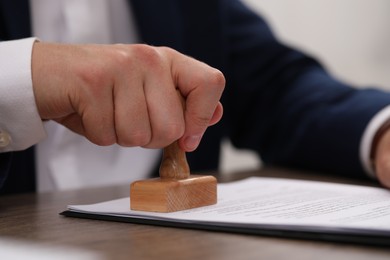 Photo of Man stamping document at table, closeup view