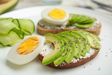 Photo of Crisp rye toast with avocado, cream cheese and quail egg on plate, closeup