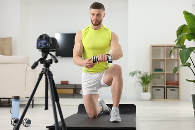 Trainer with dumbbell recording workout on camera at home