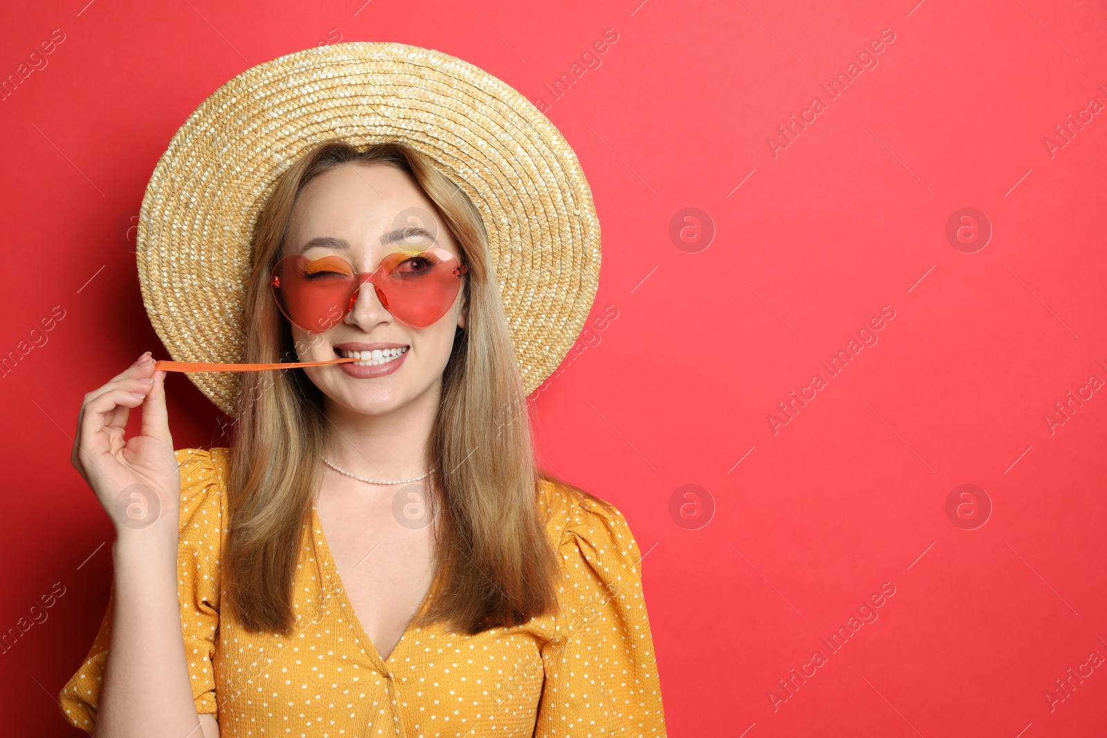 Photo of Fashionable young woman chewing bubblegum on red background, space for text