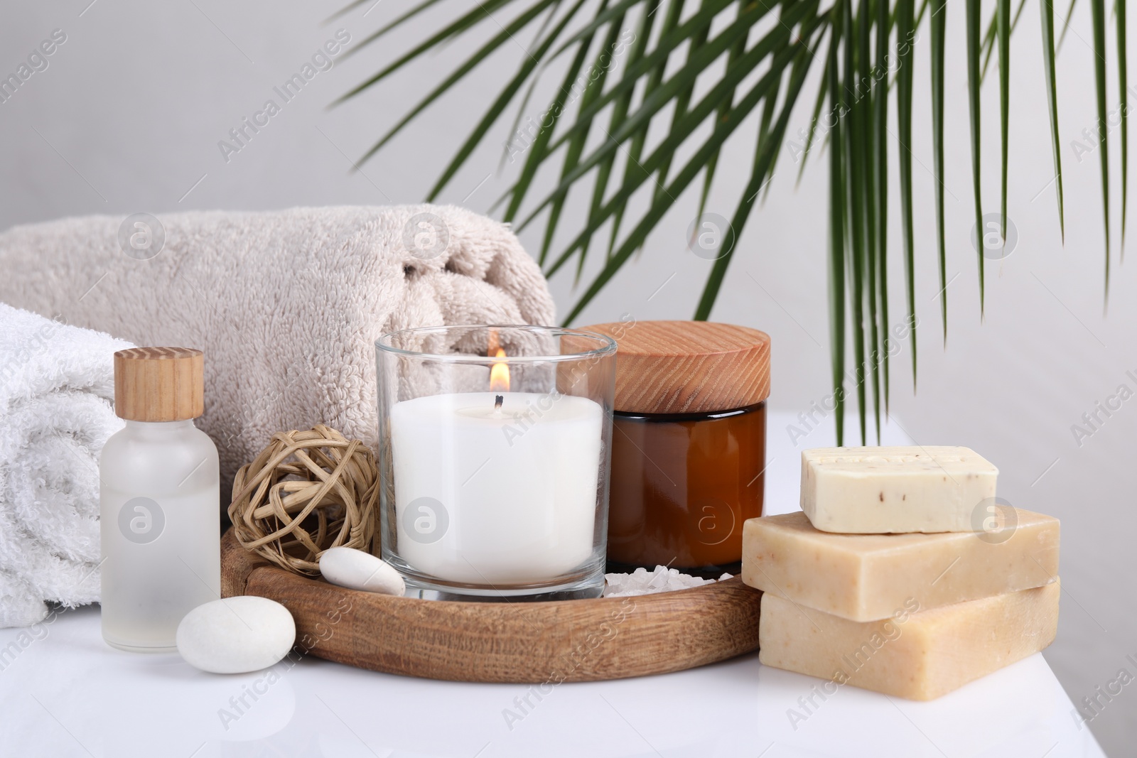 Photo of Composition with spa supplies on white table and palm leaf