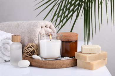 Composition with spa supplies on white table and palm leaf