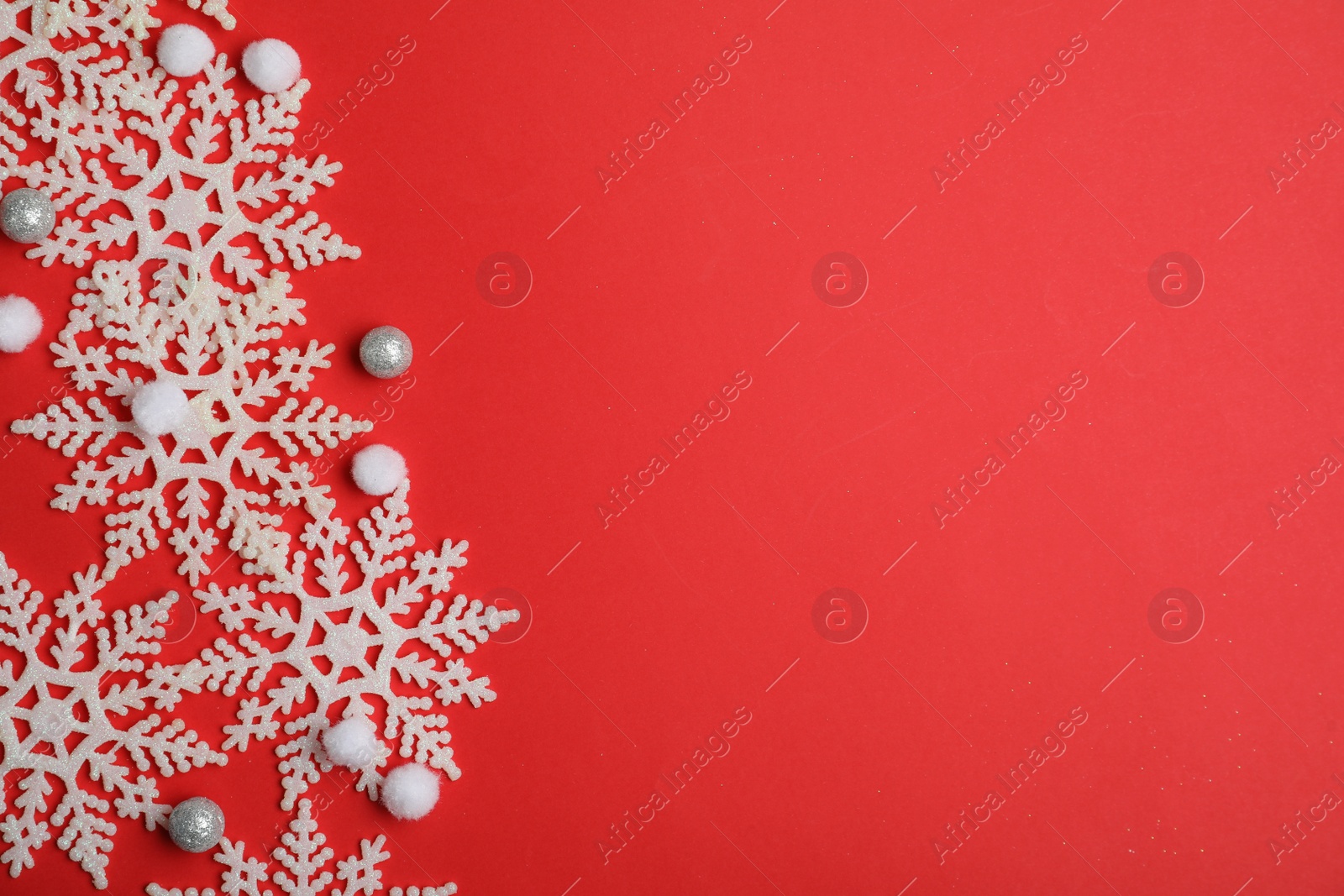 Photo of Beautiful decorative snowflakes on red background, flat lay. Space for text