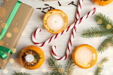 Photo of Flat lay composition with burning candles in tangerine peels as holders on white wooden table