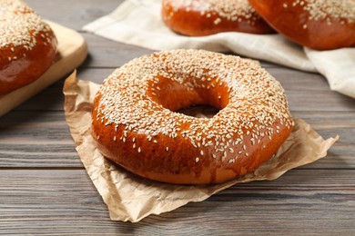 Photo of Delicious fresh bagels with sesame seeds on wooden table