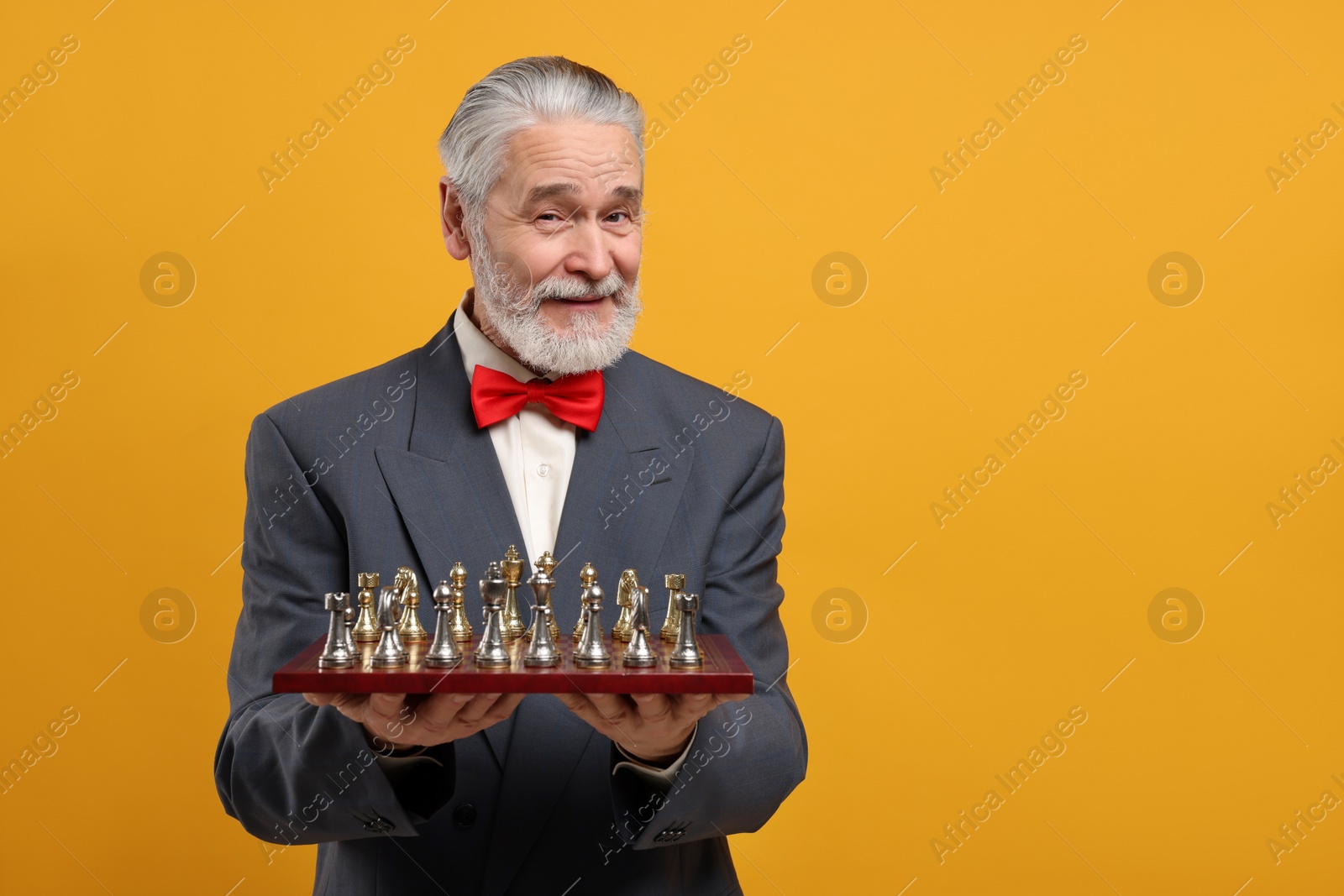 Photo of Man with chessboard and game pieces on orange background, space for text