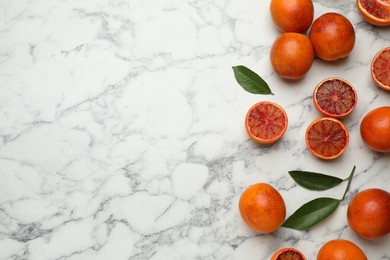 Photo of Many ripe sicilian oranges and leaves on white marble table, flat lay. Space for text