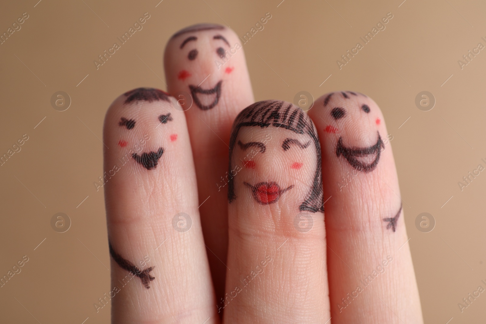 Photo of Four fingers with drawings of happy faces on brown background