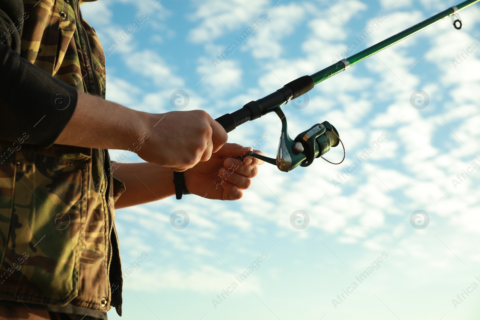 Photo of Fisherman with rod fishing under blue sky, closeup