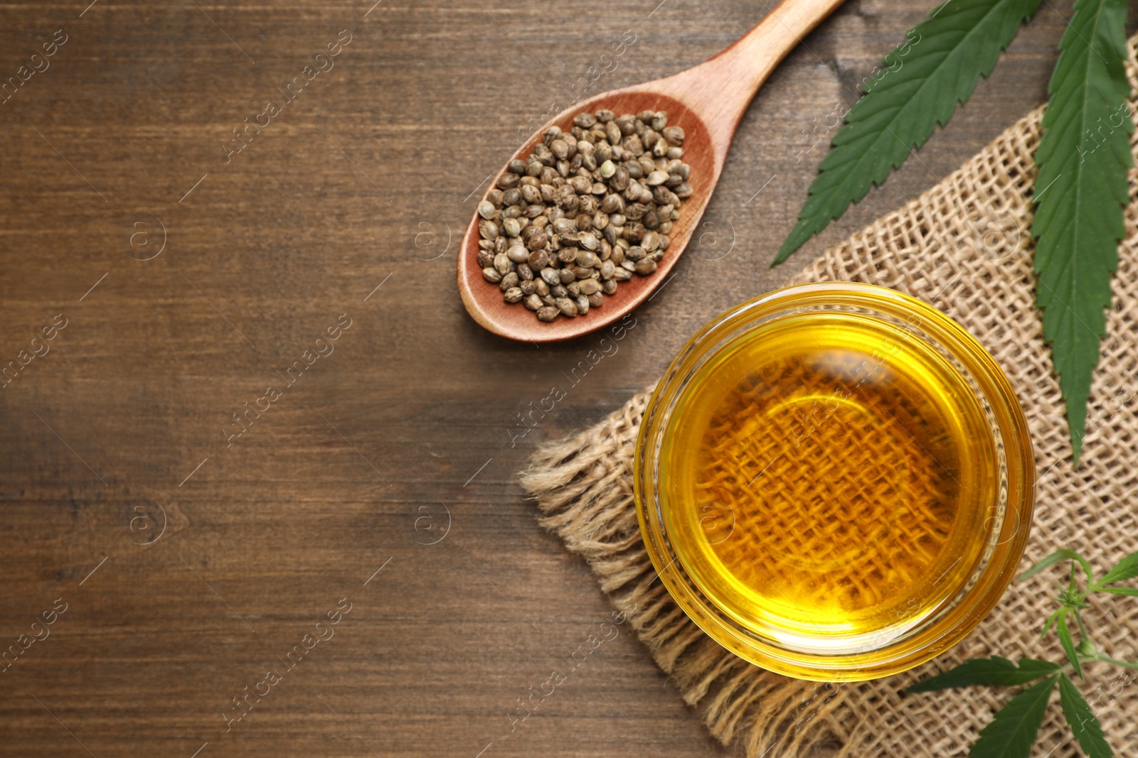 Photo of Hemp oil, leaves and seeds on wooden table, flat lay. Space for text