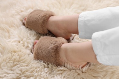 Photo of Woman in brown soft slippers at home, closeup