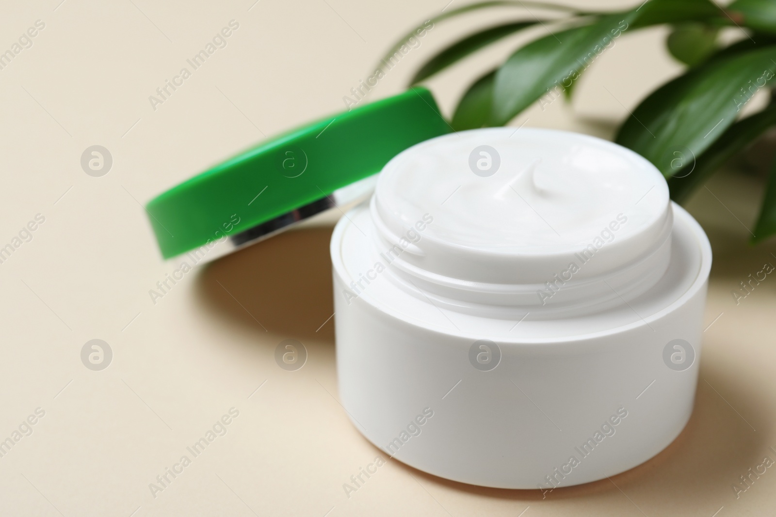 Photo of Open jar of cream on beige background, closeup