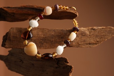 Photo of Stylish presentation of beautiful bracelet with gemstones on brown background, closeup