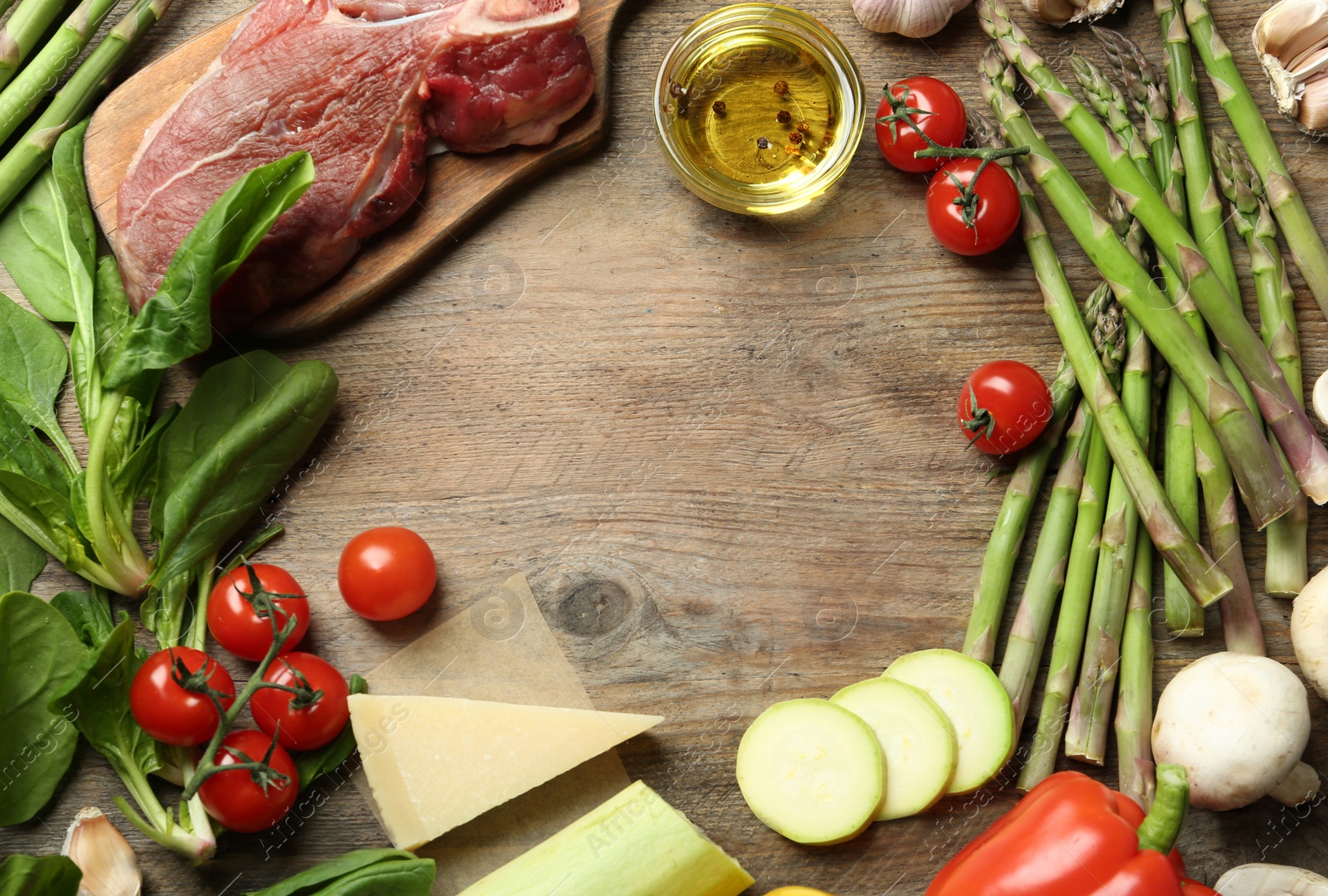 Photo of Frame made with asparagus and products on wooden table, flat lay. Space for text