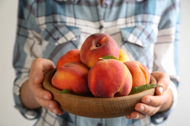 Photo of Woman with fresh sweet peaches in bowl, closeup
