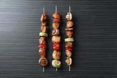 Delicious shish kebabs with vegetables on black table, top view