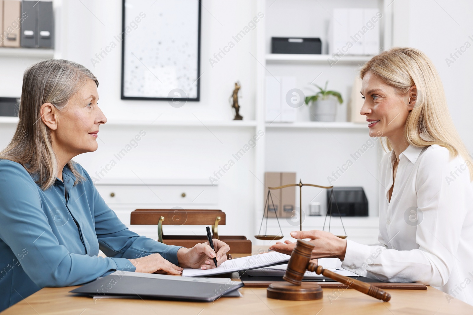 Photo of Senior woman signing document in lawyer's office