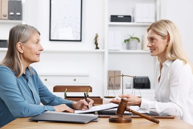 Senior woman signing document in lawyer's office