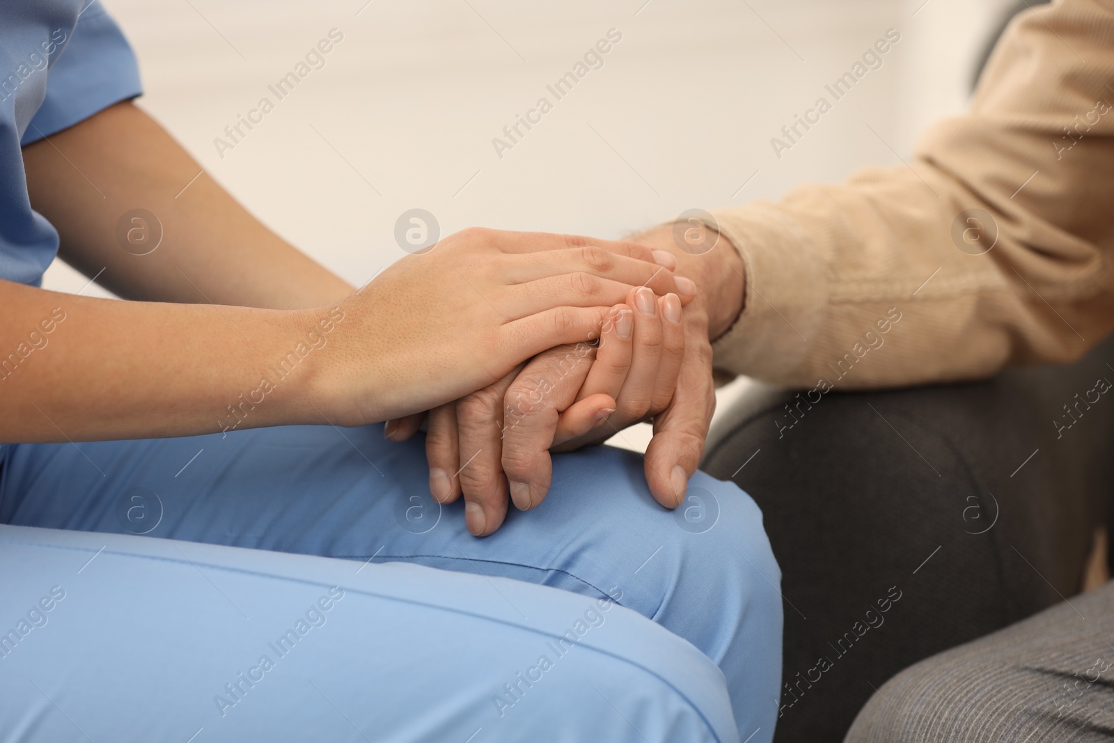 Photo of Nurse supporting elderly patient indoors, closeup view