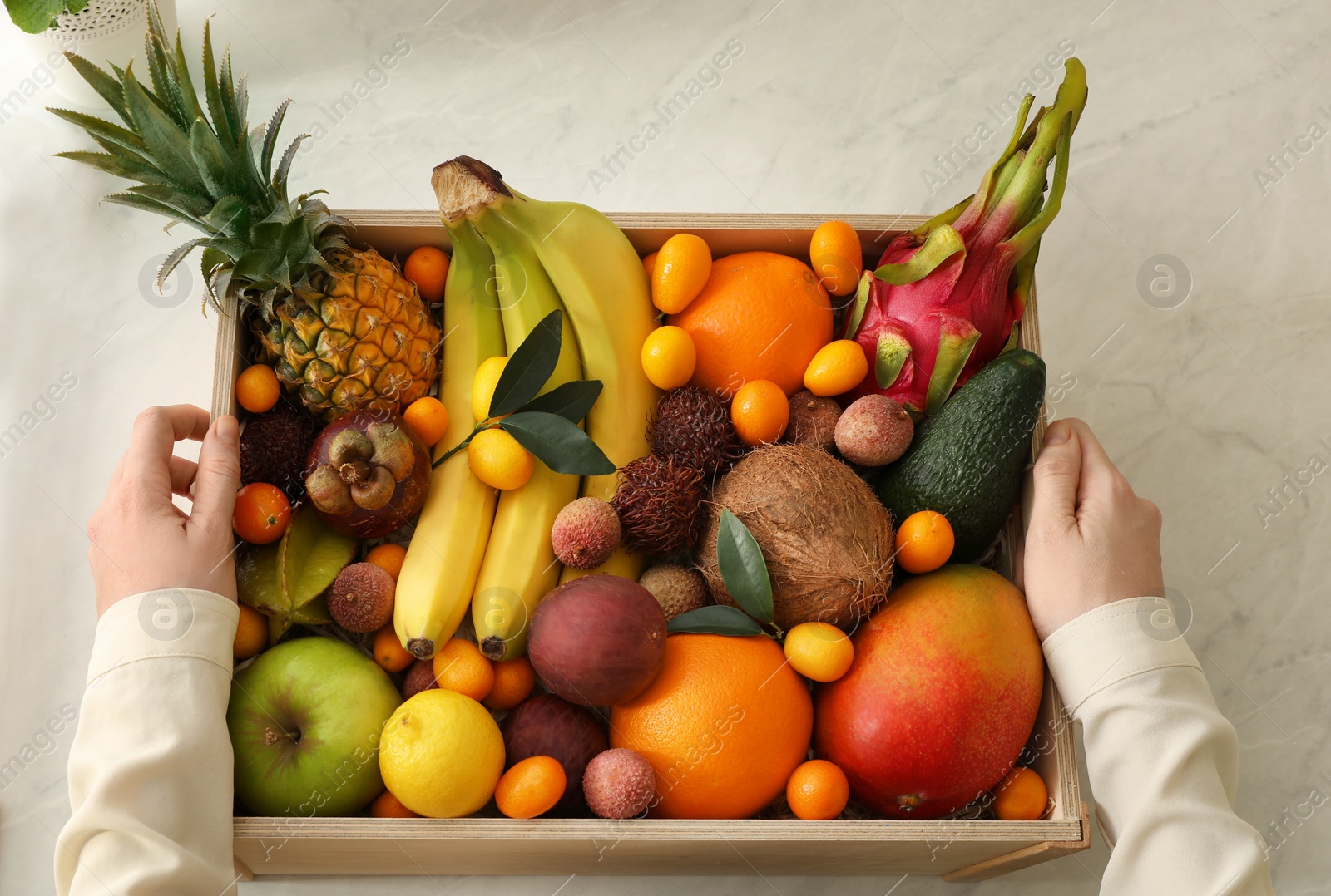 Photo of Woman with assortment of exotic fruits at table in kitchen, top view