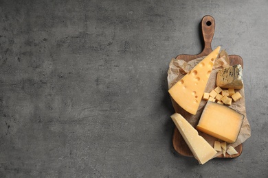 Photo of Different delicious cheeses served on grey table, top view. Space for text