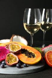 Delicious exotic fruits and wine on black table