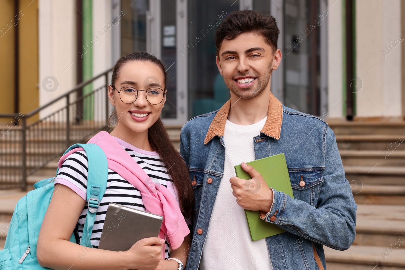 Photo of Portrait of happy young students with notebooks outdoors