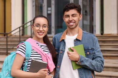 Photo of Portrait of happy young students with notebooks outdoors