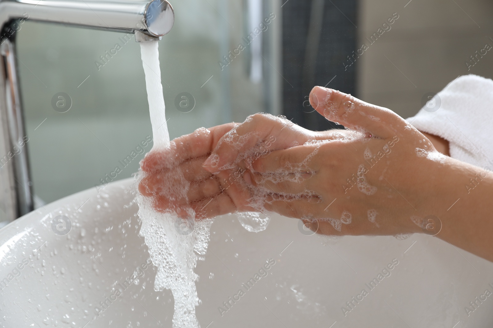 Photo of Little boy washing hands with soap over sink in bathroom, closeup