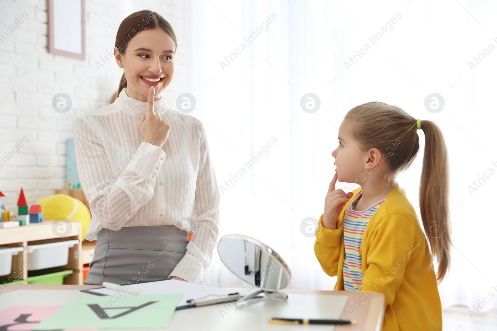 Photo of Speech therapist working with little girl in office