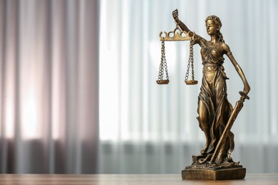 Photo of Figure of Lady Justice on table indoors, space for text. Symbol of fair treatment under law