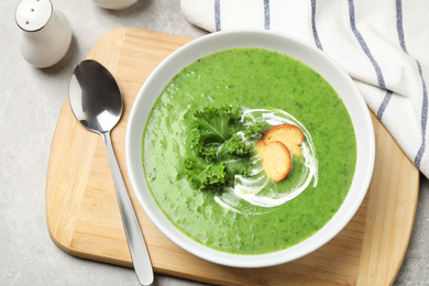 Photo of Tasty kale soup served on light grey table, flat lay