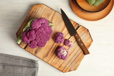 Photo of Wooden board with purple cauliflower cabbage on table, top view. Healthy food