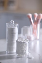 Photo of Cotton buds and pads in transparent holders on light table