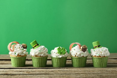 Photo of St. Patrick's day party. Tasty festively decorated cupcakes on wooden table. Space for text