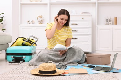 Travel blogger with book and other items planning trip at home