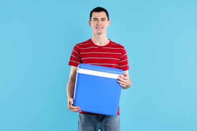 Man with cool box on light blue background