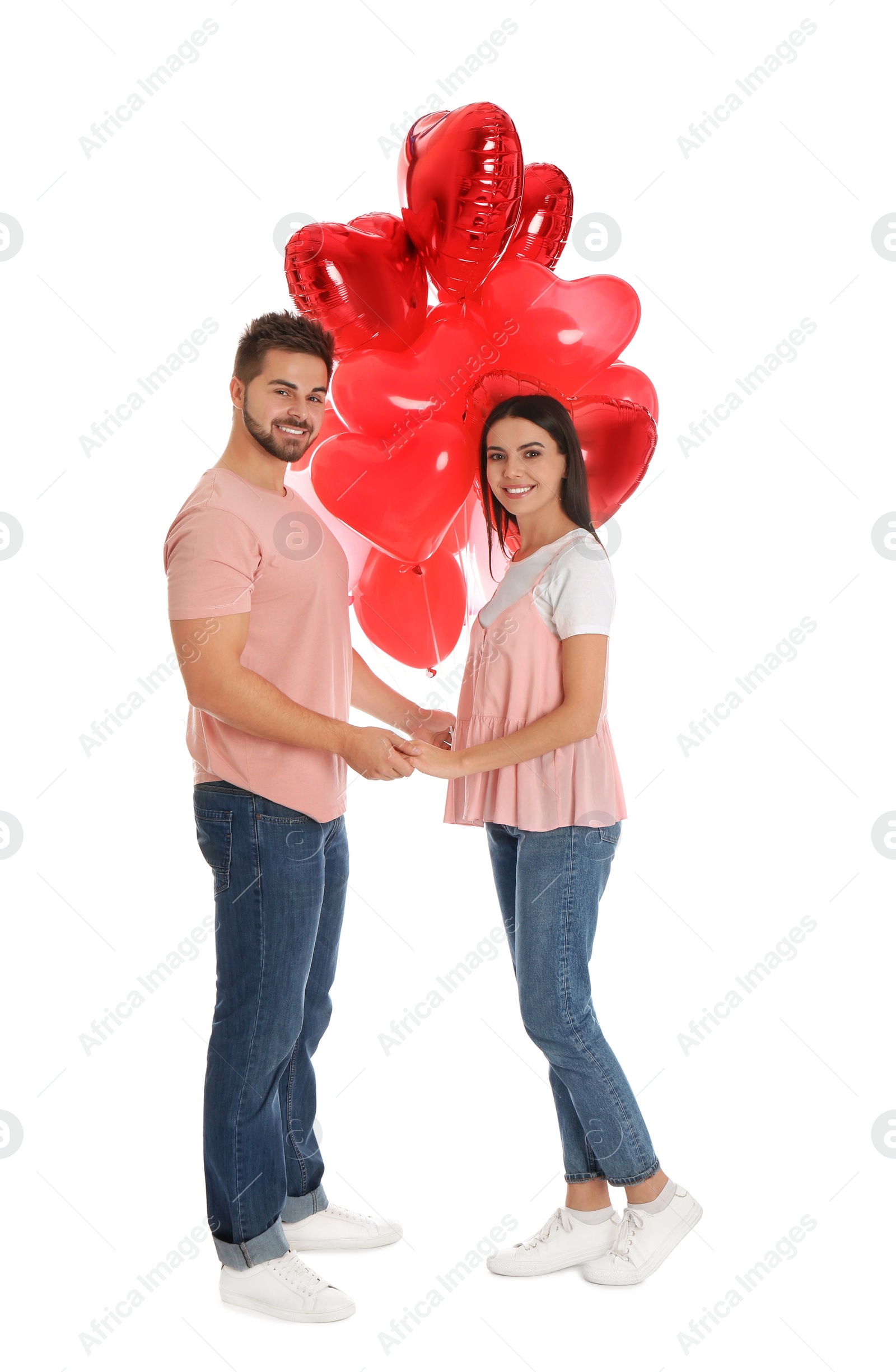 Photo of Happy young couple with heart shaped balloons isolated on white. Valentine's day celebration