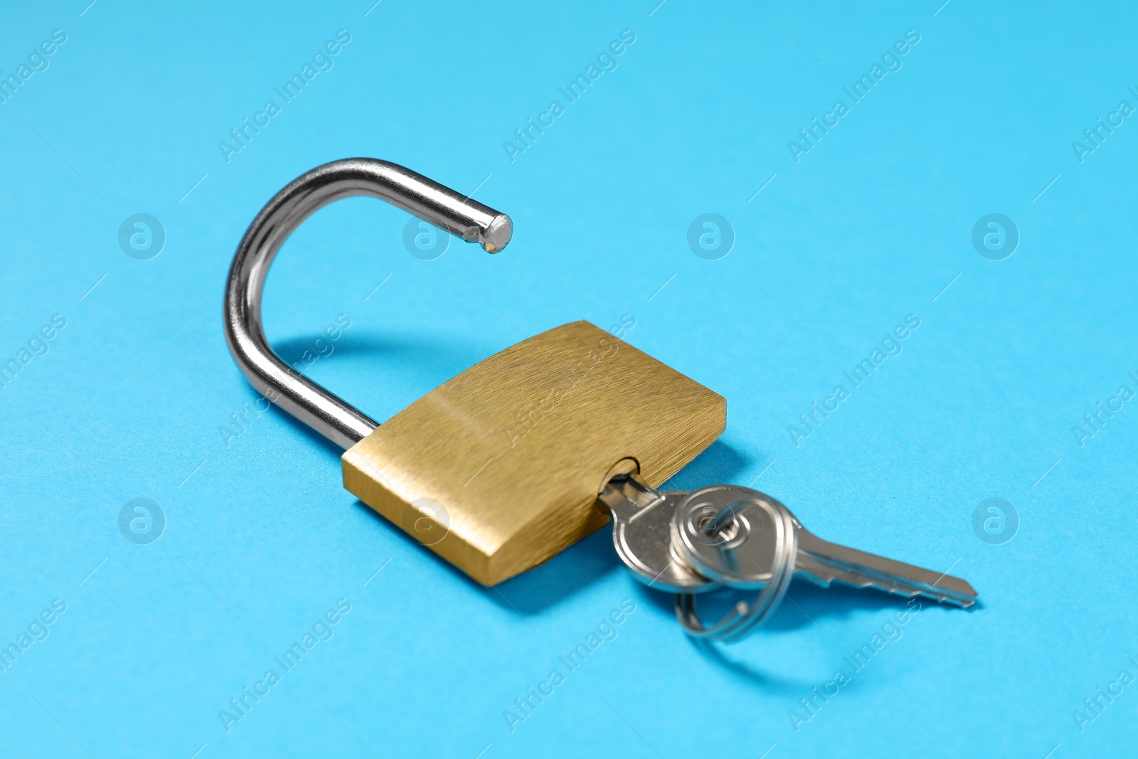 Photo of Steel padlock with keys on light blue background, closeup