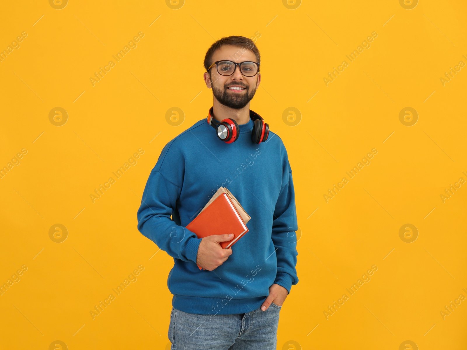 Photo of Student with headphones and books on yellow background