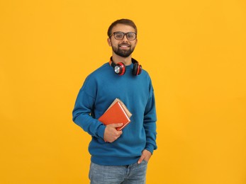 Student with headphones and books on yellow background