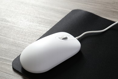 Wired mouse and mousepad on wooden table, closeup