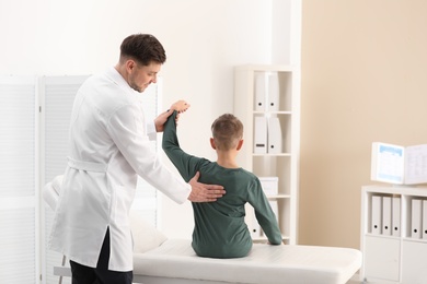 Chiropractor examining child with back pain in clinic