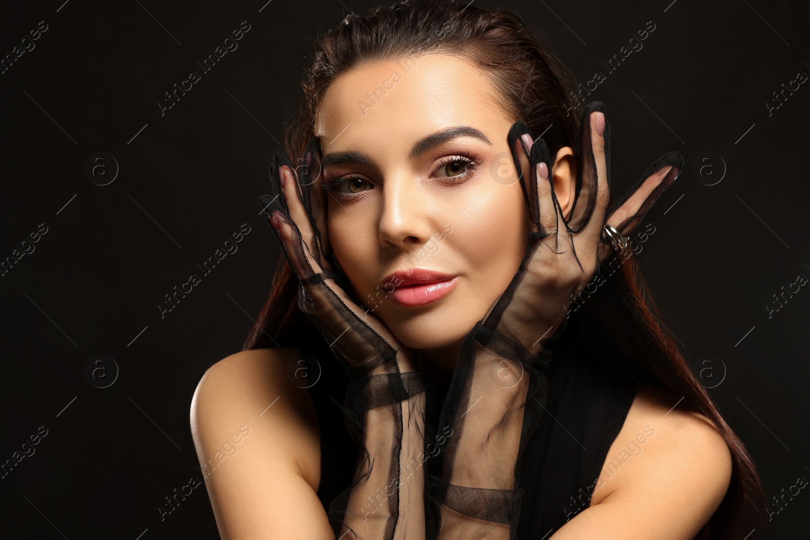 Photo of Portrait of beautiful young woman in elegant evening gloves on black background