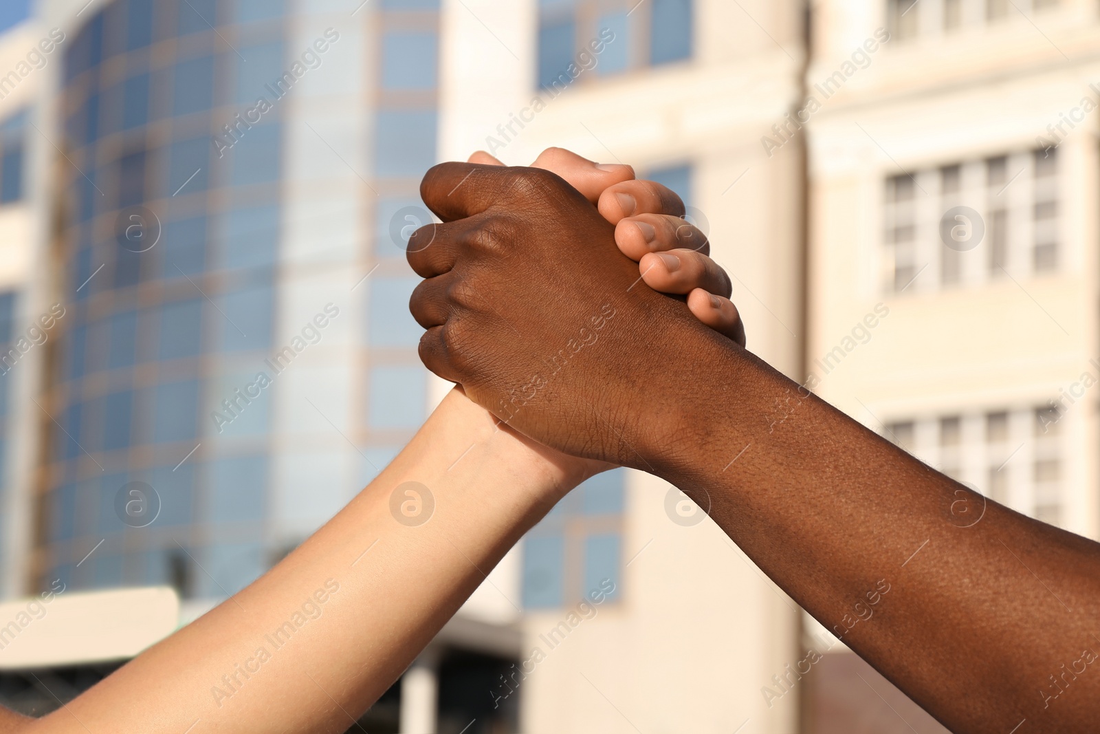 Photo of Men clasping hands on city street, closeup