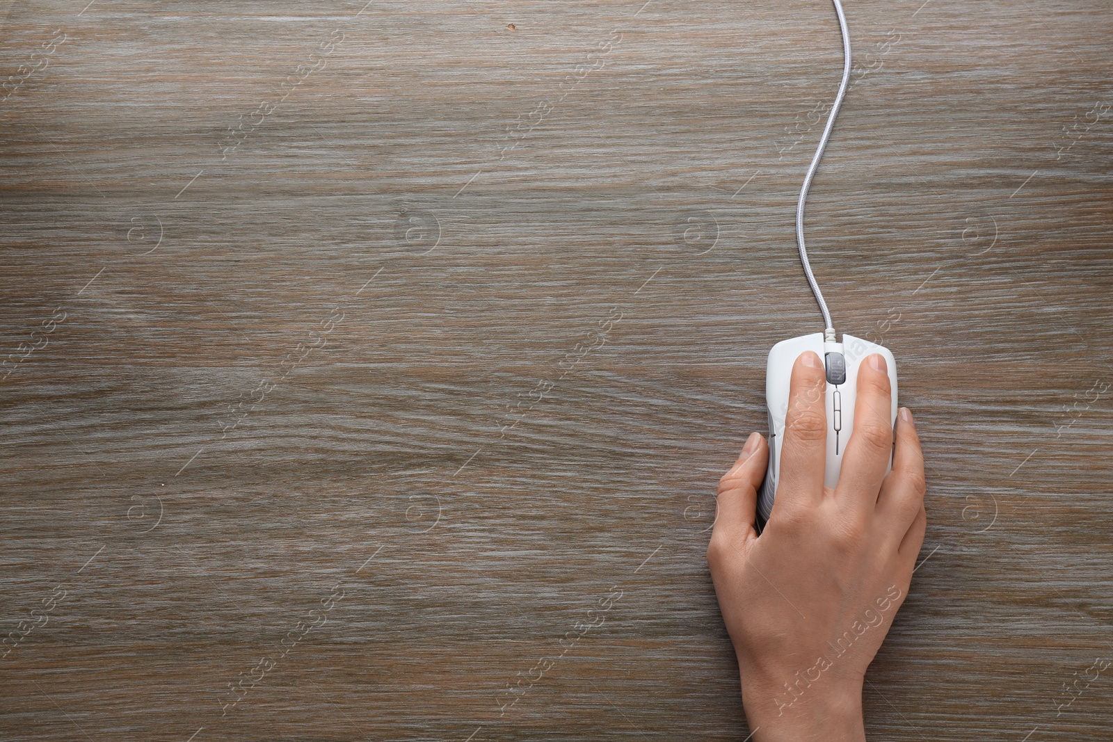 Photo of Woman using computer mouse on wooden background, top view. Space for text