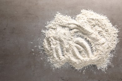 Photo of Pile of flour on grey textured table, top view. Space for text