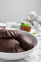 Photo of Delicious chocolate covered zephyrs in bowl on light grey table, closeup