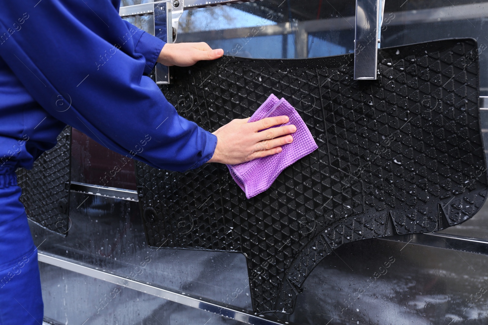 Photo of Worker wiping automobile floor mat at car wash, closeup